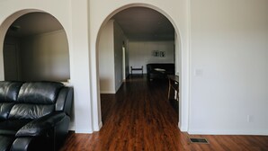 Ein geräumiger Wohnbereich mit einer dunkelbraunen Ledersofa, Holzböden und weißen Wänden.