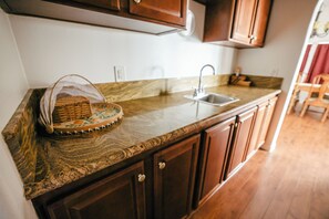 A kitchen with a granite countertop, a sink, and wooden cabinets. - Spacious Orchard Retreat with Golf Course Views & Large Patio (Moorpark)