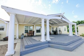 A covered patio with a wooden deck, white columns, and a clear sky. - Spacious Orchard Retreat with Golf Course Views & Large Patio (Moorpark)