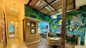 A hallway with patterned tiles, a dining area with wicker chairs, and a kitchen visible through an open door. - Casa Boutique WeLoft  San Antonio Cali (Cali)