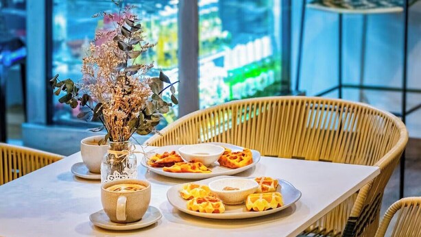 A dining table with plates of food, a vase with dried flowers, and a cup. - Casa Boutique WeLoft  San Antonio Cali (Cali)
