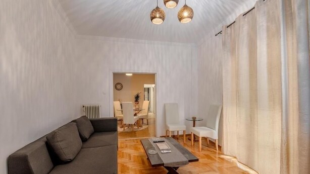 Een moderne woonkamer met een bank, een salontafel en een eethoek op de achtergrond.