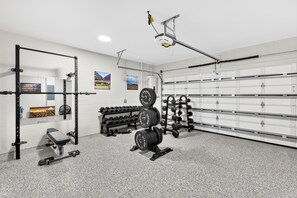 A gym with weightlifting equipment, a bench, and a wall-mounted rack. - 52 audubon (Sarasota)