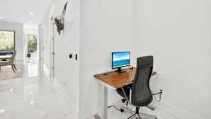 Ein moderner Arbeitsraum mit Schreibtisch, Stuhl und einem an der Wand befestigten Tierkopf.