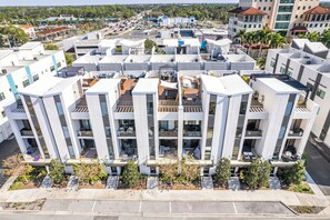 Ein modernes Mehrfamilienhaus mit Balkonen, einer flachen Dachkonstruktion und einem Parkplatz davor.