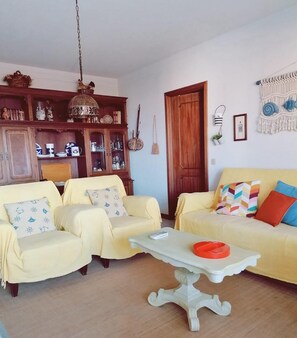 A living room with two yellow sofas, a white coffee table, and a wooden cabinet with decorative items. - Portimão Beach Apartment (Portimão)