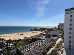 Un hotel frente al mar con vistas a la playa, paneles solares en el techo y una combinación de arquitectura tradicional y moderna.