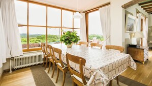 A dining area with a table, chairs, a plant, and a view through large windows. - Villa de Duintop (12 people) A dream vacation home on a dune. (Bergen aan Zee)