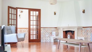 A room with a fireplace, a bench, a television, and a door with glass panels. - Maison du Bonheur, Garden Peace (Peniche)