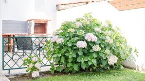 A garden with hydrangea bushes, a metal fence, and a brick oven. - Maison du Bonheur, Garden Peace (Peniche)