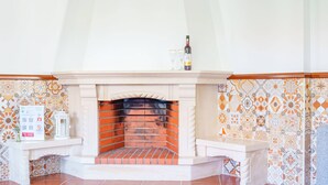 A fireplace with a tiled surround, a white mantelpiece, and a bottle of wine on top. - Maison du Bonheur, Garden Peace (Peniche)