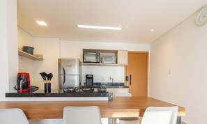 Eine kleine Küche mit Kühlschrank, Mikrowelle, Kaffeemaschine und Gasherd.