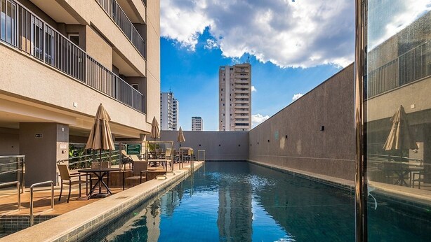 A swimming pool with lounge chairs and umbrellas, surrounded by a building with balconies. - Apt. in Condo. w/ Pool in Anapolis Grlb1405 (Anapolis)