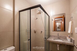 Ein modernes Badezimmer mit einer gläsernen Dusche, einem Waschbecken mit Marmorplatte und einem Spiegel mit Holzrahmen.