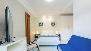 A hotel room with a bed, a TV, a desk, a chair, and a wardrobe. - Apt in Building w/ Sea View in Itapema Clzb0504 (Itapema)