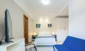 Ein Hotelzimmer mit Bett, Fernseher, Schreibtisch, Stuhl und Kleiderschrank.