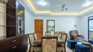 A dining area with a wooden table and chairs, a cabinet with glass doors, a ceiling fan, and a window with a view. - Apt in Building w/ Sea View in Itapema Clzb0504 (Itapema)