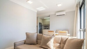 Ein modernes Wohnzimmer mit einer Couch, einem Essbereich und einer Küche im Hintergrund.