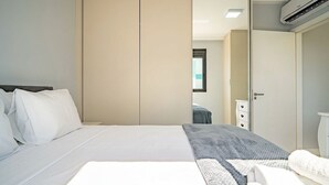 Ein Schlafzimmer mit Bett, Kleiderschrank, Nachttisch und Klimaanlage.