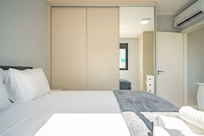 Ein Schlafzimmer mit einem Bett, einem Kleiderschrank, einem Spiegel und einer Klimaanlage.