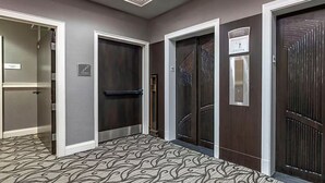 Un couloir avec trois portes, une moquette à motifs et un luminaire au plafond.