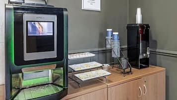 Une machine à café KREA dotée d’un écran numérique, d’un distributeur de café et d’un panneau de commande sur un comptoir en bois.