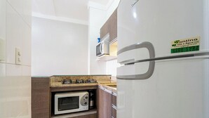 Una cocina compacta con microondas integrado, cocina a gas y refrigerador.