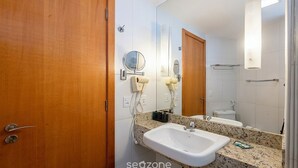 Un bagno con una porta in legno, un lavandino, uno specchio e un portasciugamani.