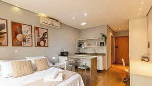 A hotel room with a bed, bedside table, and a kitchenette area with a microwave and toaster. - Studio in Condo. w/ Pool in Downtown Nwc1007 (Curitiba)