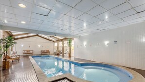 An indoor swimming pool with wooden flooring, lounge chairs, and a tiled wall. - Studio in Condo. w/ Pool in Downtown Nwc1007 (Curitiba)