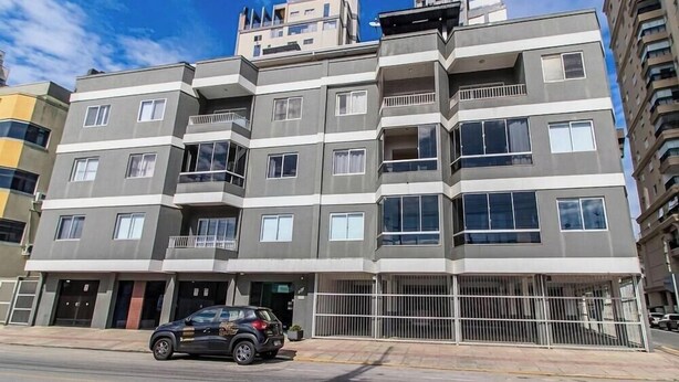 A multi-story residential building with balconies, a gated entrance, and a parked car. - Apt. in Condo. in Pereque, Porto Belo Cid0102 (Porto Belo)