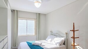 A hotel room with a bed, a window with curtains, a ceiling fan, and a coat rack. - Apt. in Condo. in Pereque, Porto Belo Cid0102 (Porto Belo)