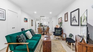 Ett modernt vardagsrum med en grön soffa, ett träbord och en matplats med stolar och ett bord.