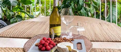 Una mesa con una botella de vino, una copa, una tabla de quesos con frambuesas y nueces, y un cuchillo.