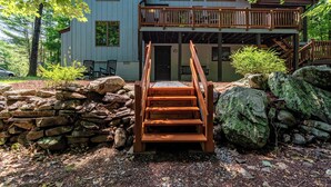 A two-story building with a wooden deck and a stone wall.