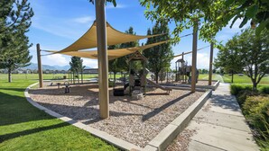 Un parque infantil con una zona sombreada, una estructura para escalar y un tobogán.