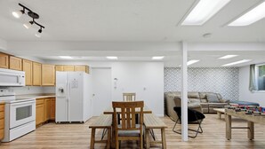 Una cocina moderna con armarios de madera, un refrigerador blanco, un microondas y una mesa de comedor con sillas.