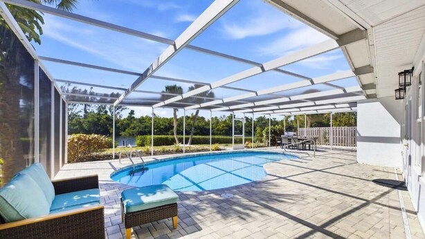 An outdoor swimming pool with a covered patio area, including seating and a table. - Waterfront Home with Pool First Floor (Sarasota)