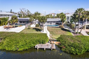 A residential area with a swimming pool, palm trees, and a dock over water. - Waterfront Home with Pool First Floor (Sarasota)