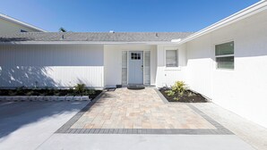 A residential house with a front entrance, a small front yard with plants, and a paved driveway. - Waterfront Home with Pool First Floor (Sarasota)