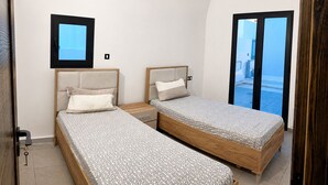 Een slaapkamer met twee bedden, een klein raam en uitzicht op het omliggende landschap.