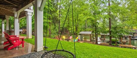 A covered patio with a swing, a red chair, and a small table.