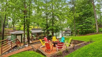 Une terrasse avec coin salon extérieur, un foyer et un petit abri de jardin.