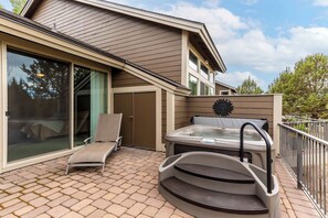 A patio with a hot tub, a lounge chair, and a sliding glass door. - Spacious Eagle Crest Condo with Resort Perks (Redmond)