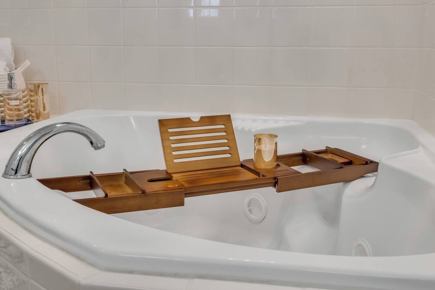 A bathroom with a white bathtub, a wooden tray with slots, and a faucet.