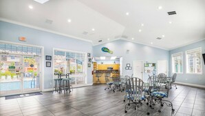 Una habitación amplia con vista a la piscina, una zona de cocina y varias sillas.