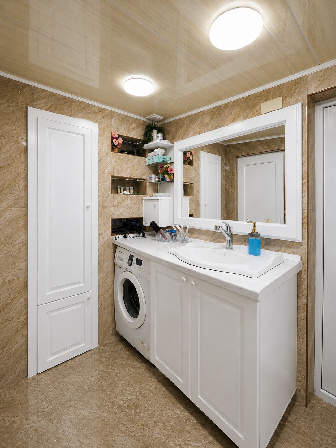 A bathroom with a washing machine, a sink, and a mirror.