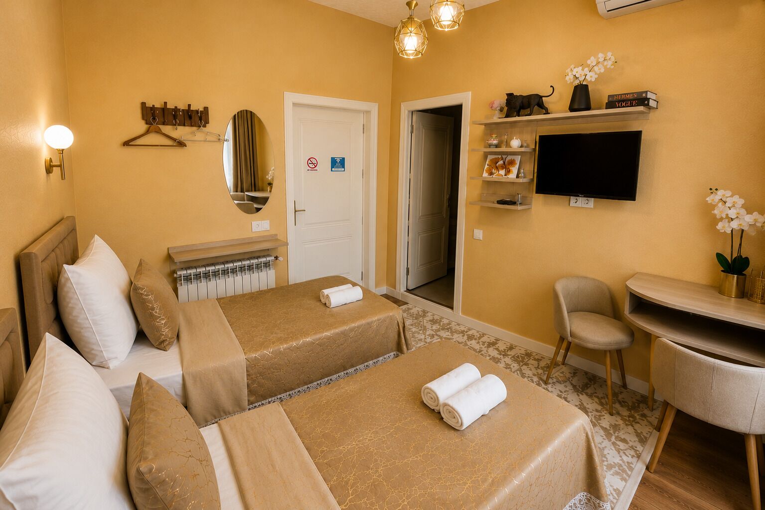 A hotel room with two beds, a desk, a chair, a TV, and a mirror.