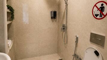 Een badkamer met douche, toilet en een rookvrij bord.