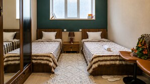 Une chambre avec deux lits, une fenêtre, un miroir, une table de chevet et une chaise.